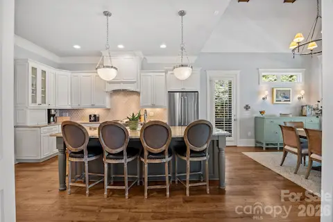 Open kitchen with large island, pendant lighting, custom cabinetry, and adjacent dining area.
