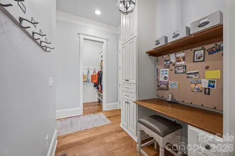 Functional drop zone includes built-in desk, storage cabinetry, and access to a walk-in closet area.