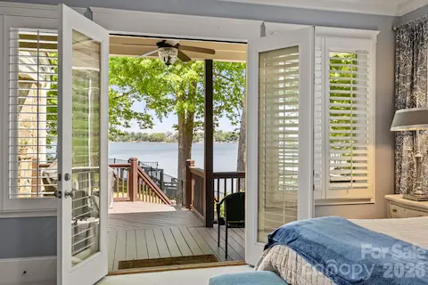 Primary suite features expansive windows and French doors that open to a covered deck by the pool.
