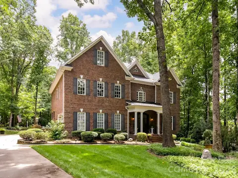 Stunning brick traditional nestled on a private wooded lot featuring timeless curb appeal, manicured landscaping, and a welcoming covered front porch.
