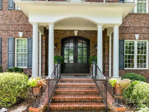 Grand covered front porch with stately columns and elegant double entry doors creates a warm and impressive welcome home.