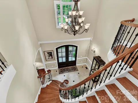 Impressive two-story foyer showcases a sweeping staircase, rich hardwood floors, and an elegant chandelier that makes a stunning first impression.