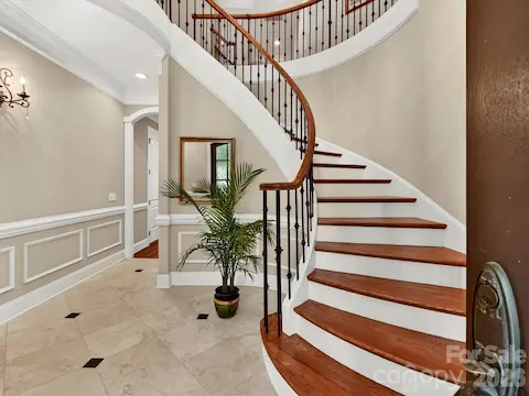 Impressive two-story foyer showcases a sweeping staircase, rich hardwood floors, and an elegant chandelier that makes a stunning first impression.