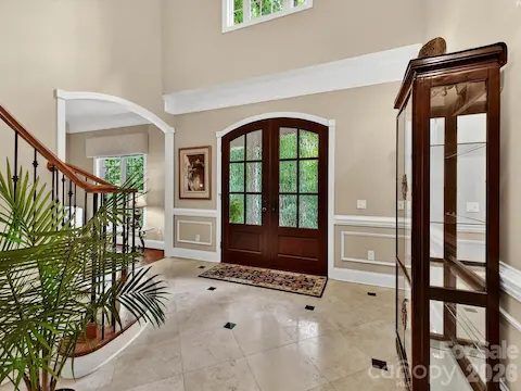 Impressive two-story foyer showcases a sweeping staircase, rich hardwood floors, and an elegant chandelier that makes a stunning first impression.