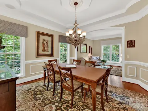 Elegant formal dining room features extensive crown molding, tray ceiling details, hardwood floors, and seamless flow into the adjoining living spaces for effortless entertaining.