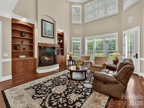 Stunning two-story great room features soaring ceilings, custom built-ins, expansive windows, and a cozy fireplace with seamless flow into the kitchen and breakfast area.