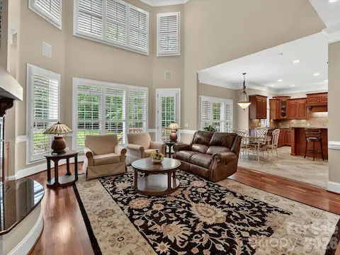 Stunning two-story great room features soaring ceilings, custom built-ins, expansive windows, and a cozy fireplace with seamless flow into the kitchen and breakfast area.