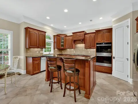 Chef’s kitchen showcases rich custom cabinetry, granite countertops, stainless steel appliances, a large center island, and an open layout designed for effortless entertaining.