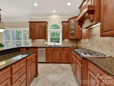 Chef’s kitchen showcases rich custom cabinetry, granite countertops, stainless steel appliances, a large center island, and an open layout designed for effortless entertaining.