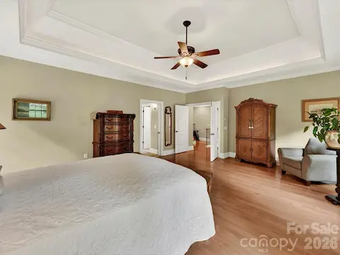 Spacious primary suite features hardwood floors, elegant tray ceilings, abundant natural light, and a peaceful retreat-like atmosphere.