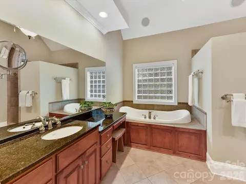 Spa-inspired primary bath features dual vanities, granite countertops, a dedicated makeup area, and an oversized tiled walk-in shower.