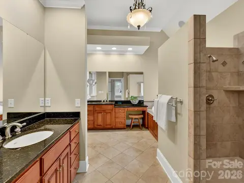 Spa-inspired primary bath features dual vanities, granite countertops, a dedicated makeup area, and an oversized tiled walk-in shower.