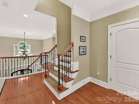 Elegant staircase landing with hardwood floors, detailed iron balusters, and access to the private third-level living space.