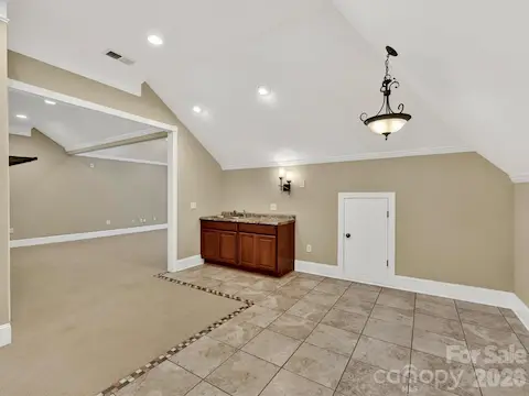 Expansive third-level bonus room offers incredible flexibility with vaulted ceilings, recessed lighting, built-in wet bar, and abundant space for entertaining, recreation, or a home theater.