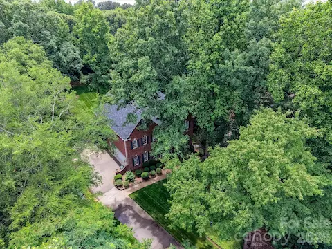 Drone views highlight the home’s serene wooded setting, mature landscaping, and exceptional privacy on a spacious lot.