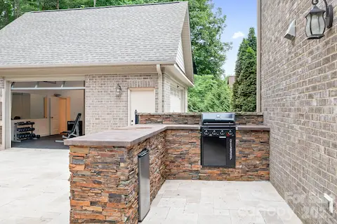 Outdoor kitchen features built in gas grill and fridge