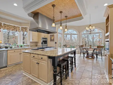 The kitchen offers an inviting center island equipped with a gas cooktop and pendant lights, along with wall ovens and ample cabinet space.
