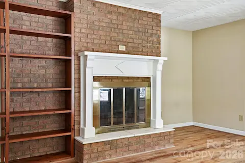 Classic wood-burning fireplace brings rustic comfort and warmth, complemented by built-in shelves for display and storage.