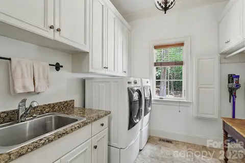 Generous Laundry with iron board, sink and cabinets!
