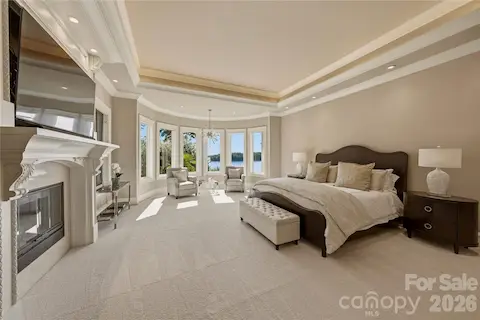 Main-level primary suite with panoramic lake views & a fireplace.
