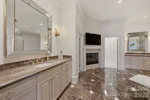 Main-level primary ensuite with two vanities, fireplace, and private water closet. 
