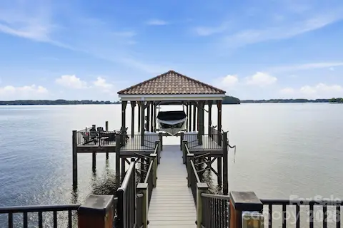 Covered dock with a tile roof, boatlift, & seating area. 