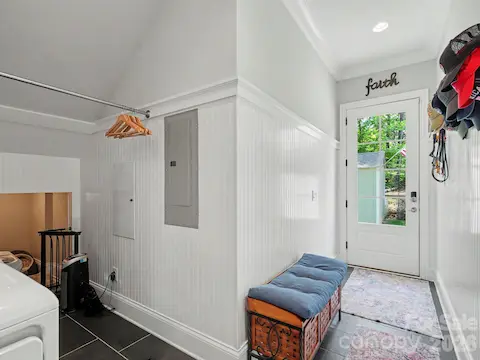 Utility/mud room with dog sleeping room or storage space leads to side door inside fence