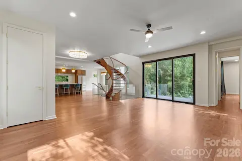 Bright open-concept living room with oak hardwood floors and oversized sliding glass doors overlooking the pool
