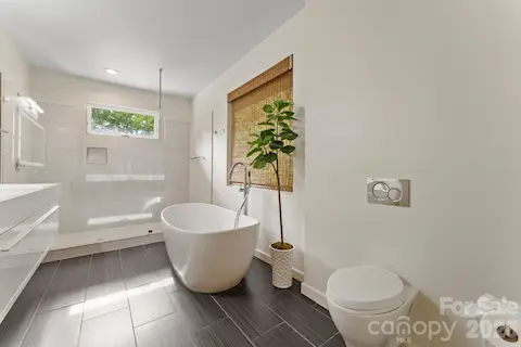 Primary en-suite spa bath featuring dual vanities, walk-in shower, and soaking tub