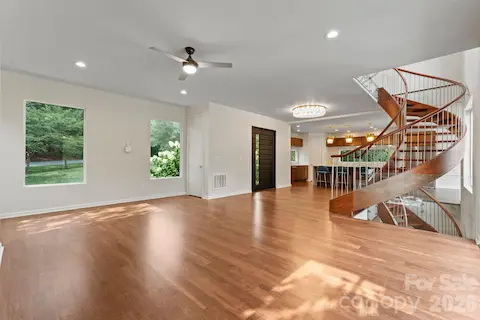Two-story great room with oak spiral staircase, paneled glass, gas fireplace, and hardwood floors