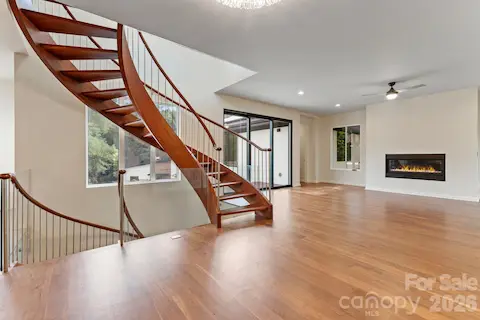 Two-story great room with oak spiral staircase, paneled glass, gas fireplace, and hardwood floors