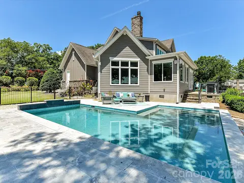 Resort-style saltwater pool with expansive travertine decking creates a stunning outdoor retreat overlooking serene waterfront views, perfect for relaxing and entertaining.