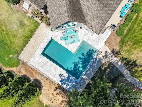 Resort-style saltwater pool with expansive travertine decking creates a stunning outdoor retreat overlooking serene waterfront views, perfect for relaxing and entertaining.