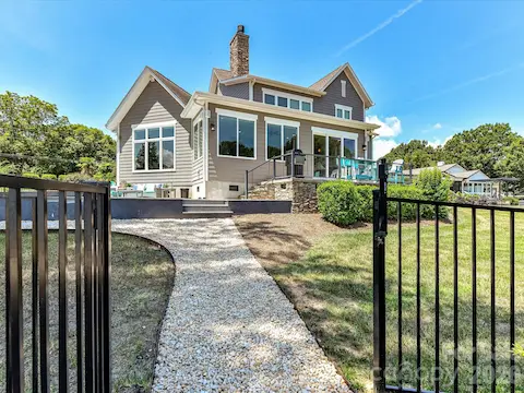 The beautifully landscaped backyard offers multiple outdoor living spaces, a private pool, and direct access to the waterfront for the ultimate lakeside lifestyle.