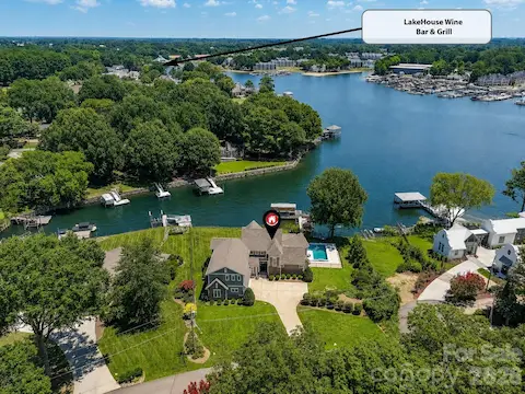 Aerial view highlights the home's exceptional waterfront setting with quick access to open water and nearby LakeHouse Wine Bar & Grill. (Virtually enhanced lake levels)