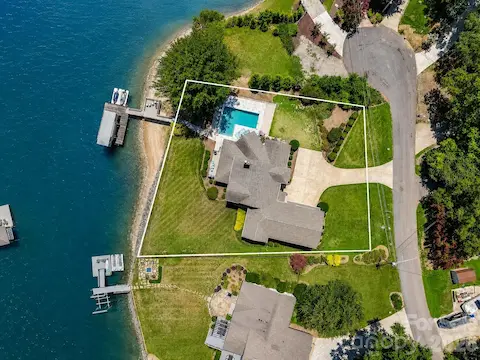 Aerial view with property lines clearly illustrates the expansive waterfront homesite, private dock, pool, and generous outdoor living spaces. (Virtually enhanced lake levels)