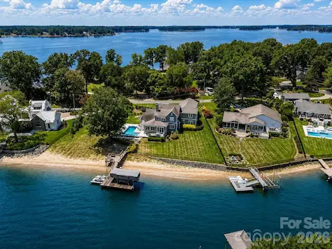 Aerial view showcases the property's private sandy beach, dock, pool, and exceptional waterfront setting with expansive Lake Norman views. (Virtually enhanced lake levels)