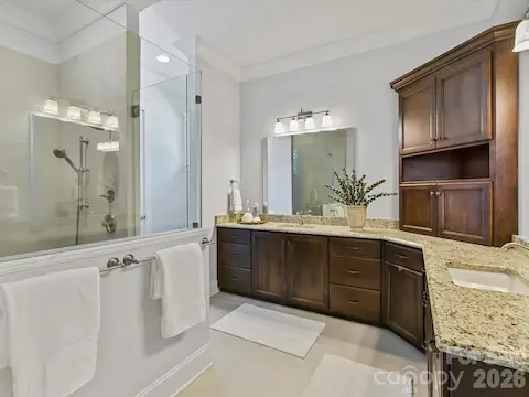 Spa-inspired primary bath features dual granite vanities, a spacious tiled walk-in shower, abundant cabinetry, and generous counter space for everyday luxury.