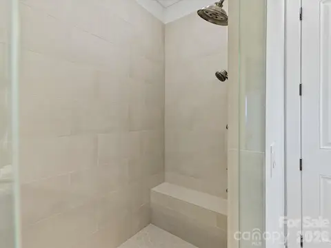 Oversized tiled walk-in shower with frameless glass enclosure, built-in bench seating, and dual showerheads creates a luxurious spa-like experience.