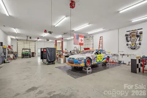 Large automotive workshop with lift, surface plate and hanging air and electric lines.