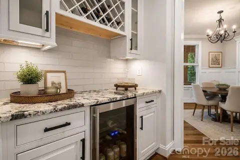 bar area with wine rack and fridge connects DR and kitchen area- virtually staged