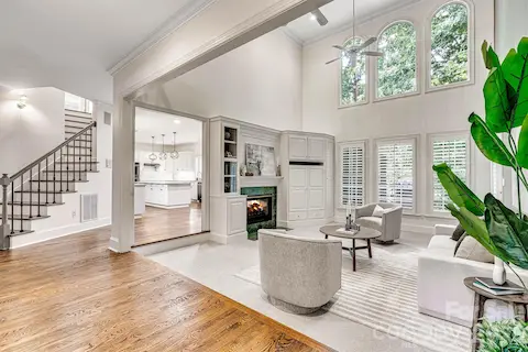Light-filled family room with soaring two-story ceiling, fresh neutral carpet, built-ins, plantation shutters and a 2-sided gas fireplace.