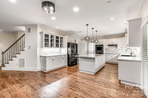 Renovated kitchen with refinished hardwoods, abundant cabinetry, glass display cabinets, under-cabinet lighting, designer tile backsplash & updated fixtures.