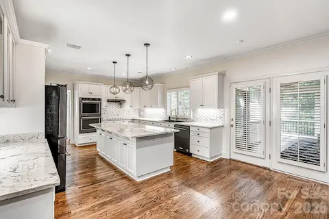 Refinished hardwoods, crisp white cabinetry, granite countertops, under-cabinet lighting, custom tile backsplash, plantation shutters & a window over the sink.