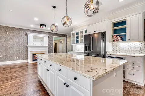 Large center island with granite countertops & stylish pendant lighting.