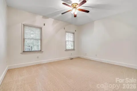 Main-level guest bedroom overlooking the private rear yard with recently installed neutral carpet.