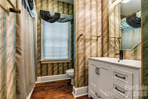 Main-level guest bath with updated vanity & refinished hardwood floors.