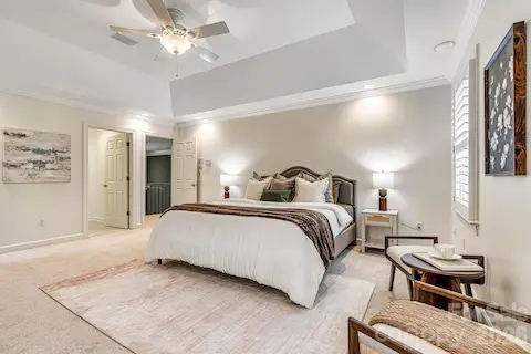 Spacious primary suite with a deep tray ceiling, plantation shutters and recently installed neutral carpet.