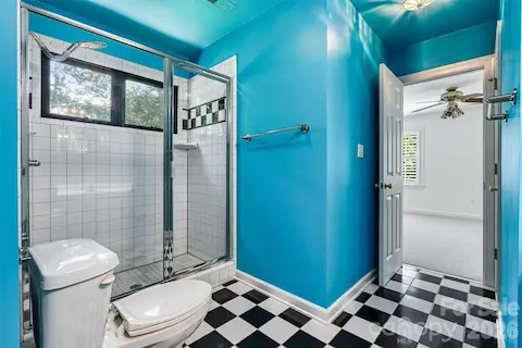 Jack-and-Jill bath showcases classic black-and-white checkered tile flooring, a fully tiled walk-in shower & a cheerful pop of color.