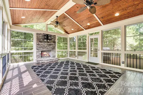 Custom 3-season porch with vinyl windows, tile floors & a stacked stone fireplace that creates a warm and inviting gathering space year-round.